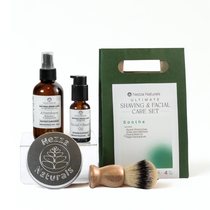 Nezza Naturals Ultimate Shaving and Facial Care Set with Aftershave, Face & Beard Oil in glass, Glycerin Shaving Soap in metal tin, vegan shaving brush, and gift packaging on a white background.